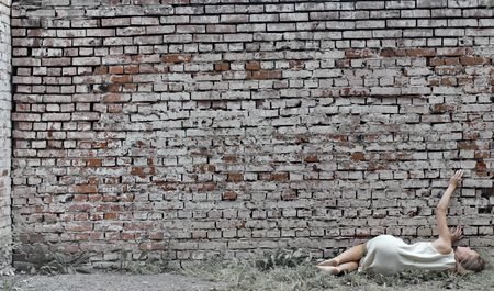 Girl in a gray dress on brick wall backgroundの写真素材