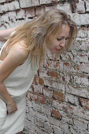 Girl in a gray dress on brick wall backgroundの写真素材