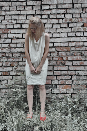 Girl in a gray dress on brick wall backgroundの写真素材