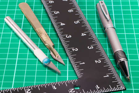 A variety of cutting tools used in arts and crafts photographed against a green cutting mat backgroundの写真素材