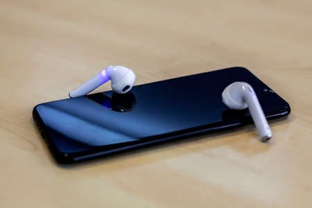 Smartphone with earphones on wood background