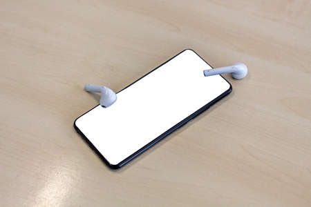 Smartphone with earphones on wood background