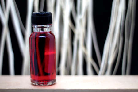 Bottles with perfume and fresh rose on table against blurred backgroundの写真素材