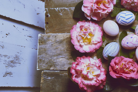 backgrounds made with camellias, green leaves and hand-painted easter eggsの写真素材