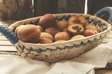 basket of freshly picked apricots on old wooden tableの写真素材