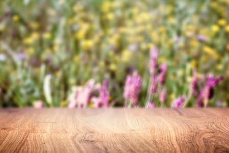 A wooden table and in the background a field with wild flowers can be sensed