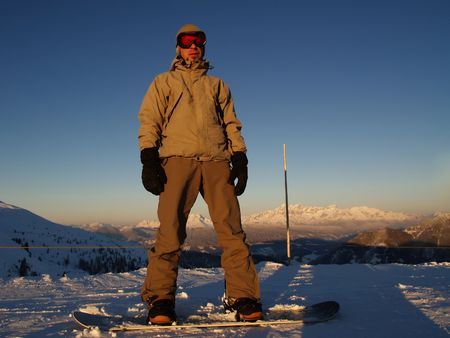 A snowboarder standing on the top of the hill.の写真素材