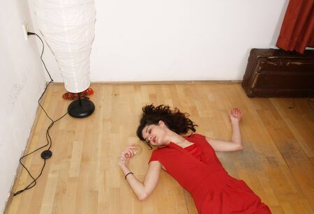 Woman in red dress lying on the ground with win glassの写真素材