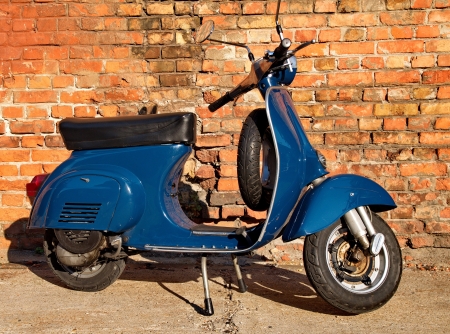 Blue scooter in front of a red brick wallの写真素材