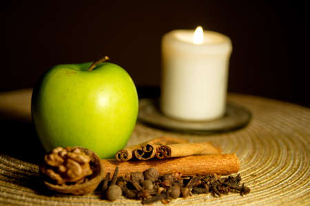 Green apple, cinnamon, walnut and a candleの写真素材