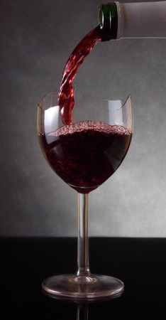 Pouring red vine into a broken glassの写真素材