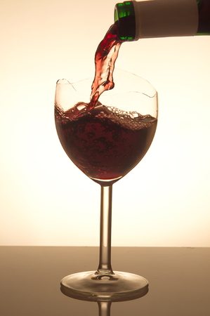 Pouring red vine into a broken glassの写真素材