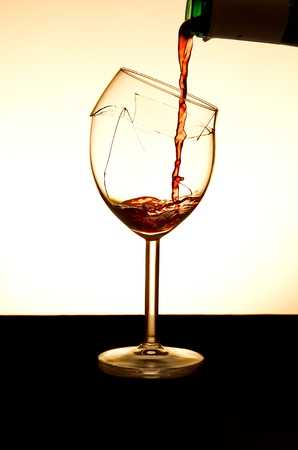 Pouring red vine into a broken glassの写真素材