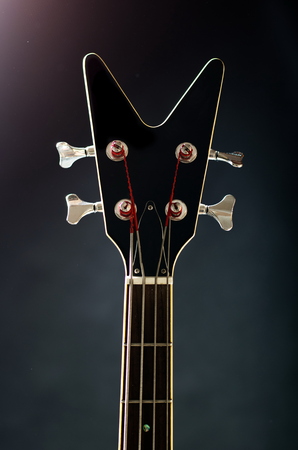 Neck of a black bass guitar with flares
