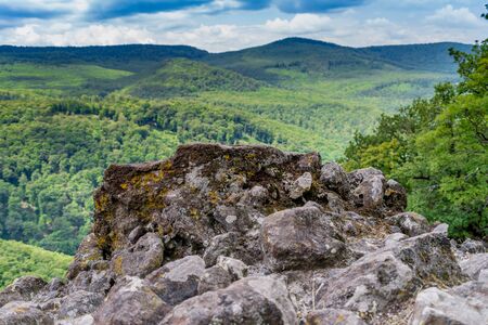 Rocks on a tree covered mountain and cloudy skyの写真素材