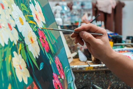The artist's hand with a brush paints a picture in an art studioのeditorial素材