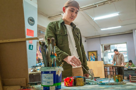 04/22/2022, Almaty, Almaty region, Kazakhstan. The artist mixes paints in the palette with a brush in an art workshop.のeditorial素材