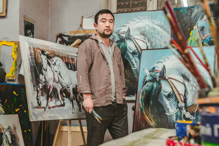 04/22/2022, Almaty, Almaty region, Kazakhstan. An artist with a brush in his hand stands in an art studioのeditorial素材