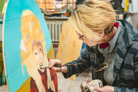 04/22/2022, Almaty, Almaty region, Kazakhstan. The artist holds a brush in his hand and paints a picture in an art studio.のeditorial素材