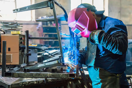 The welder works with metal at the factory