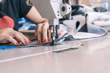 The seamstress sews at the sewing machine, threads the fabric. Women's handsの写真素材
