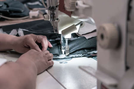 The seamstress sews at the sewing machine, threads the fabric. Women's handsの写真素材