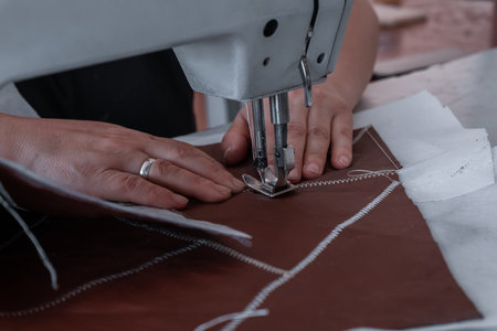The seamstress sews at the sewing machine, threads the fabric. Women's hands