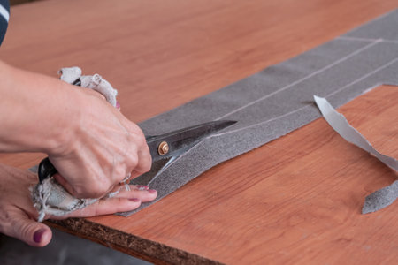 A cutter cuts fabric with scissors in a sewing workshop