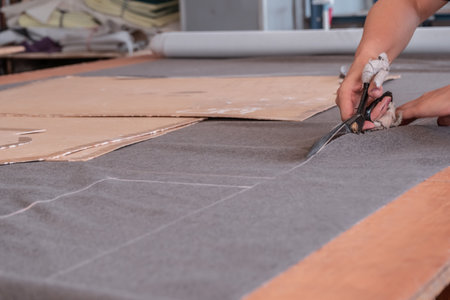 Cutter cuts fabric with scissors in a sewing workshop