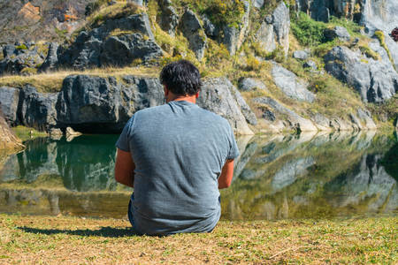 A young man sitting in front of a lake on a spring day, portrait, la arboleda, basque country