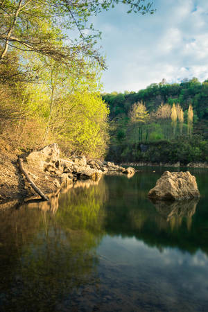 a lake during spring with some rocks as foreground, la arboleda, basque countryの写真素材