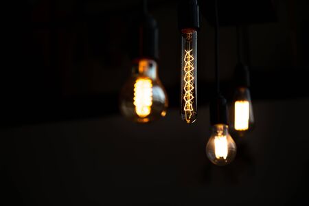 Bare bulb. Worm bokeh lights and dark background. Analog life. Vintage styled tungsten lamp in the...