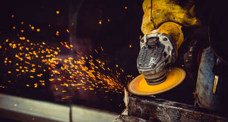 worker man hand with gloves using tool for grinding and cutting metal making sparks in workshop isolated on black backgroundの写真素材
