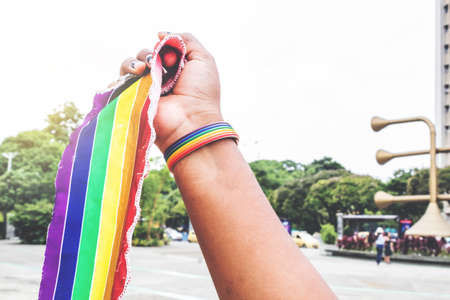 hand of person with tatoo with lgbt flag and bracelet in the city park in sunny dayの写真素材