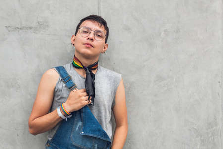 teen gay boy with glasses looking at camera on gray city wallの写真素材