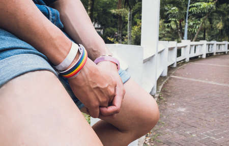 hands of gay boy with lgbt bracelet sitting in the cityの写真素材
