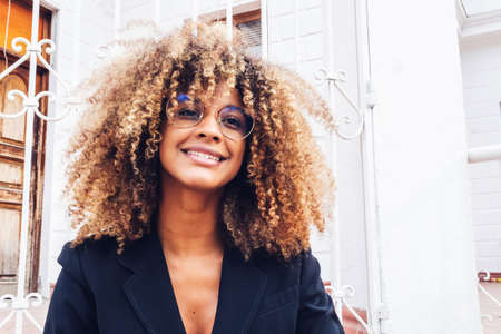elegant african american business woman with glasses smiling in the city isolated on a white house
