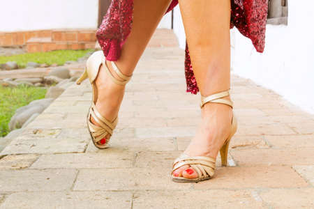 feet of tango dancer woman posing with red dress in home garden dancing outdoors in the cityの写真素材
