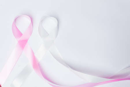 Pink ribbon fight against breast cancer and white ribbon to fight violence against women on isolated white background with space for text.の写真素材