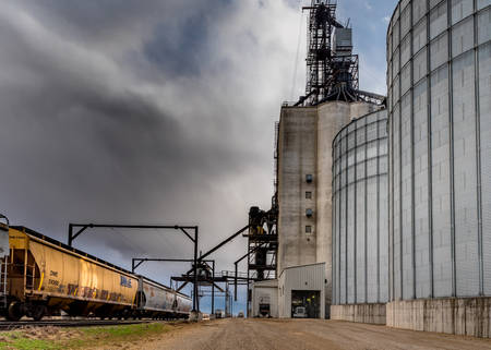 Swift Current, SK/Canada- 10 May, 2019:  Semi unloading under stormy skies at Paterson Grain Terminal in Swift Current, SK, Canada with railwayのeditorial素材