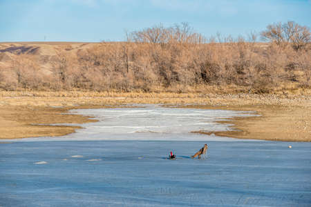 Saskatchewan Landing, SK, Canada- March 29, 2020: Male fisherman ice fishing on Lake Diefenbakerのeditorial素材