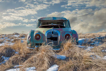 Abandoned car in the tall grass on a snowy hillside in Neidpath, SKのeditorial素材