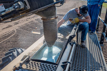 Swift Current, SK/Canada- May 15, 2020: Young farmer loading fertilizer into the Bourgault air drill...