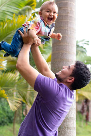 father holding his son high.baby smiling with her fatherの写真素材