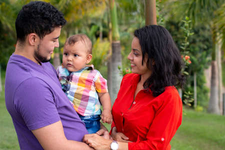 Happy parents taking care of their baby in a beautiful park full of nature.の写真素材