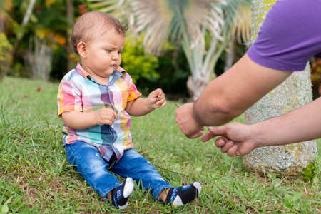 Baby playing in a garden full of nature with her fatherの写真素材