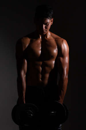 Latin and muscular man using weights. Shirtless man lifting weights. man musclesの写真素材
