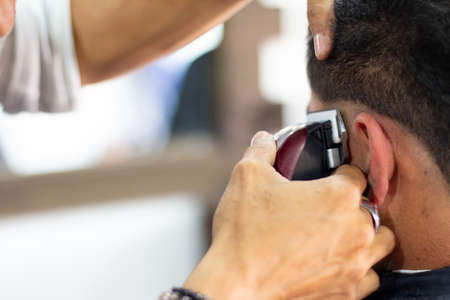 Professional barber passing electric clippers to a customer.の写真素材