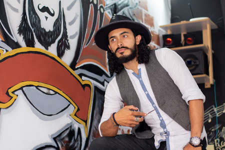 Barber with hat and elegant dress next to the drawing of his barber shop. Man with beard and moustache.の写真素材