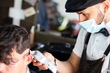 Latin barber using face mask, using a razor on client. Hair Stimulation growthの写真素材